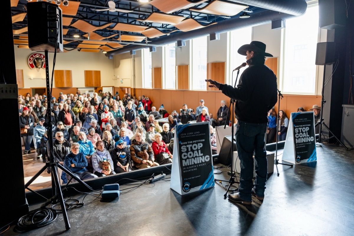 Corb Lund speaking to a packed hall of supporters